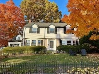 view of front of house featuring fence, a chimney, and a front lawn