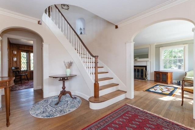 foyer entrance featuring a healthy amount of sunlight, arched walkways, stairs, and wood finished floors