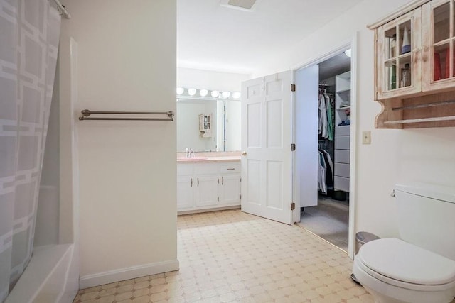 full bath with toilet, vanity, baseboards, a spacious closet, and tile patterned floors