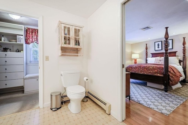 ensuite bathroom with toilet, a baseboard heating unit, visible vents, and ensuite bathroom