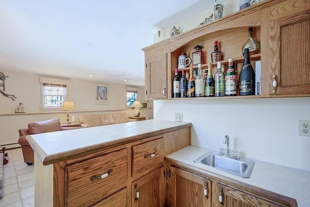 kitchen featuring light countertops, brown cabinetry, a peninsula, and a sink