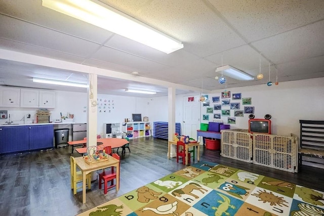 playroom with dark wood-style floors and a drop ceiling