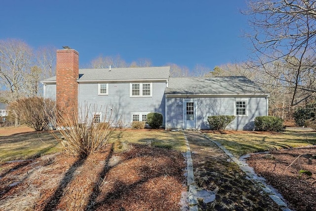 rear view of property with a chimney and a yard