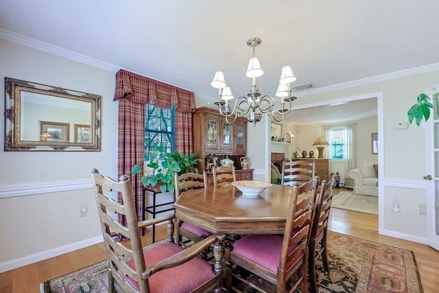 dining space with crown molding, an inviting chandelier, and wood finished floors