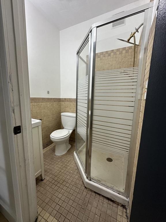 99 Allston St, Lawrence, MA 01841 - full bath featuring a stall shower, vanity, toilet, wainscoting, and tile walls