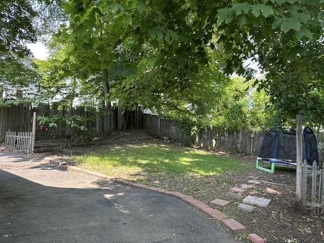 99 Allston St, Lawrence, MA 01841 - fenced backyard with a trampoline and a patio area