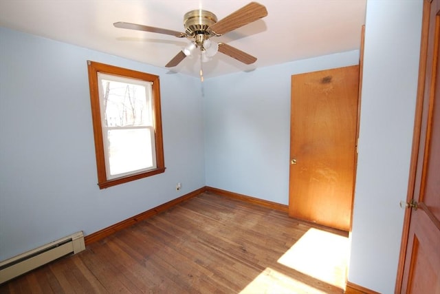 empty room featuring a baseboard radiator, a ceiling fan, wood finished floors, and baseboards