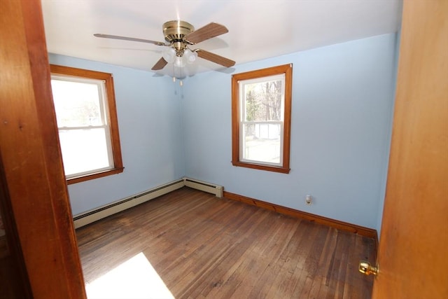spare room featuring hardwood / wood-style floors, a healthy amount of sunlight, a baseboard heating unit, and baseboards