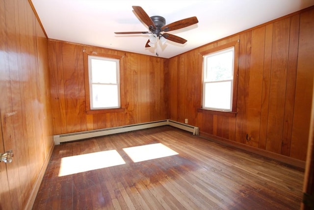 unfurnished room featuring a baseboard radiator, hardwood / wood-style floors, a ceiling fan, and a healthy amount of sunlight