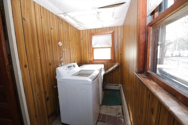 clothes washing area featuring washer and clothes dryer, wood walls, laundry area, and a baseboard radiator