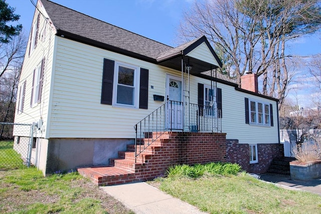 bungalow-style home with fence, a shingled roof, and a chimney