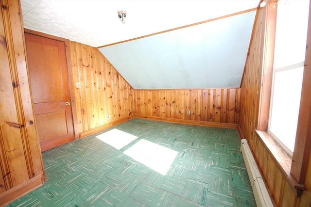 bonus room featuring wood walls, baseboard heating, baseboards, and lofted ceiling