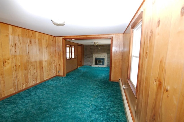 unfurnished living room with wood walls, a fireplace, carpet flooring, and baseboard heating