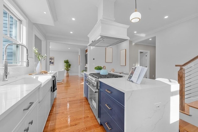 kitchen with custom range hood, blue cabinets, stainless steel stove, white cabinetry, and hanging light fixtures