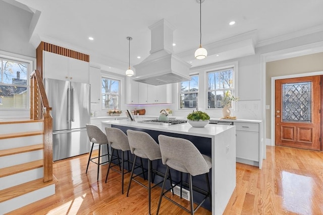 kitchen with white cabinetry, plenty of natural light, decorative light fixtures, appliances with stainless steel finishes, and custom exhaust hood