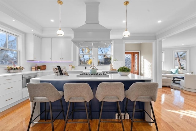 kitchen featuring white cabinets, pendant lighting, light hardwood / wood-style flooring, and a wealth of natural light