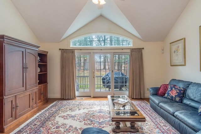 living room with ceiling fan, light wood-type flooring, and vaulted ceiling