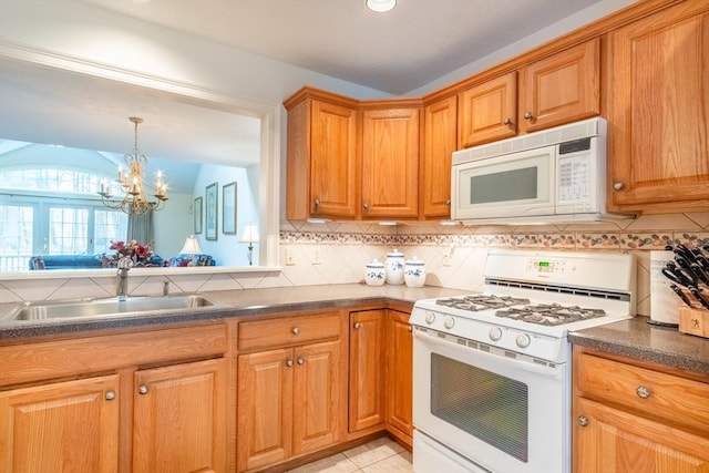 kitchen featuring white appliances, pendant lighting, a notable chandelier, backsplash, and sink