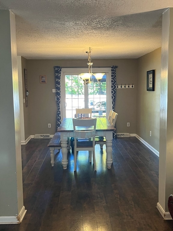 dining area with dark wood-type flooring and a textured ceiling