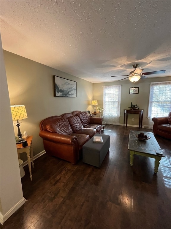 living room with a textured ceiling, plenty of natural light, ceiling fan, and dark wood-type flooring