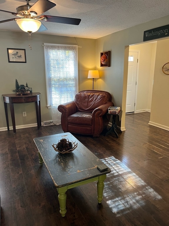 living room with a textured ceiling, dark hardwood / wood-style floors, and ceiling fan