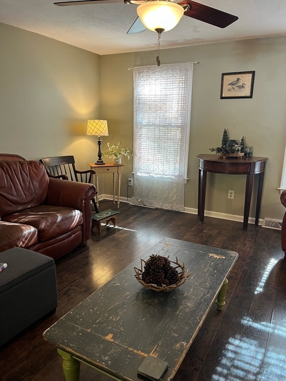 living room featuring dark hardwood / wood-style floors, ceiling fan, and a textured ceiling