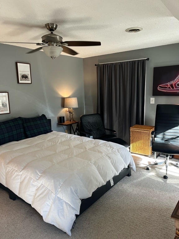 carpeted bedroom with ceiling fan and a textured ceiling