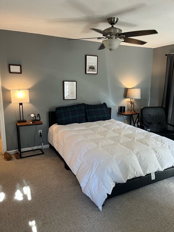 carpeted bedroom with ceiling fan and a textured ceiling