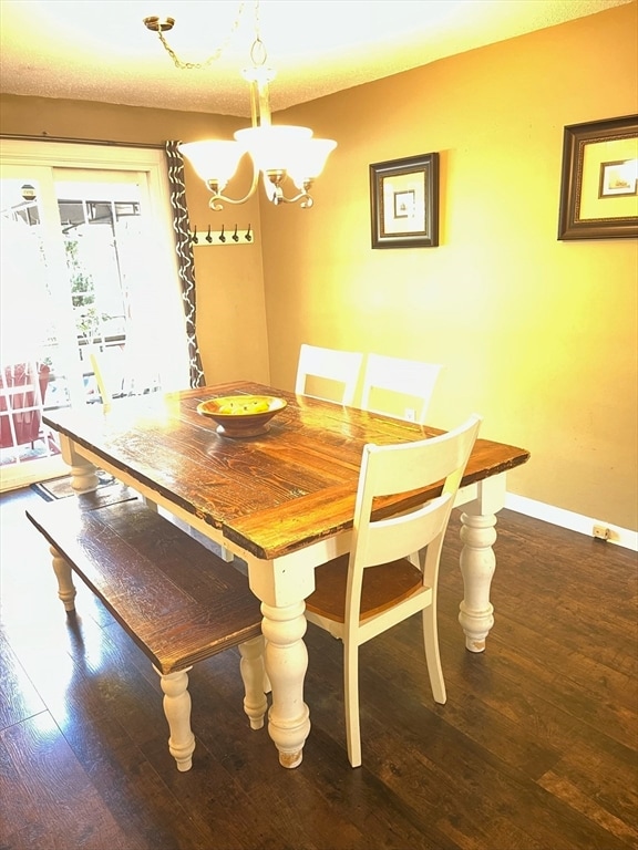 dining space with dark hardwood / wood-style flooring, a textured ceiling, and an inviting chandelier