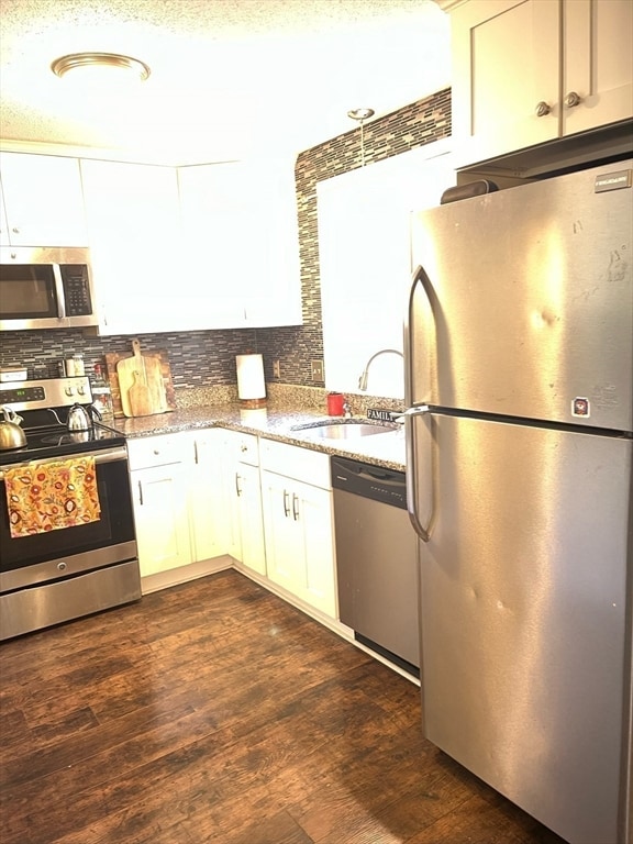 kitchen featuring white cabinets, sink, dark hardwood / wood-style flooring, light stone counters, and stainless steel appliances