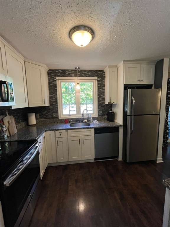 kitchen with dark hardwood / wood-style floors, decorative light fixtures, a textured ceiling, white cabinets, and appliances with stainless steel finishes