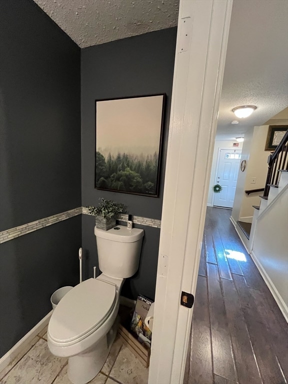 bathroom with toilet, a textured ceiling, and hardwood / wood-style flooring