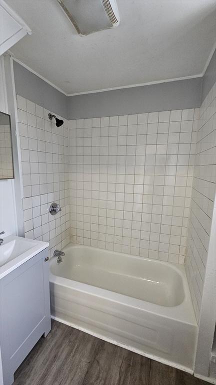 bathroom featuring hardwood / wood-style flooring, vanity, and tiled shower / bath