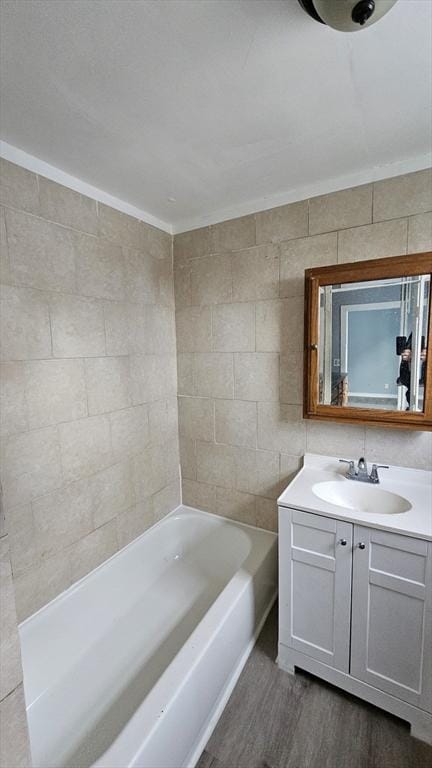 bathroom featuring shower / bath combination, ornamental molding, vanity, hardwood / wood-style flooring, and tile walls