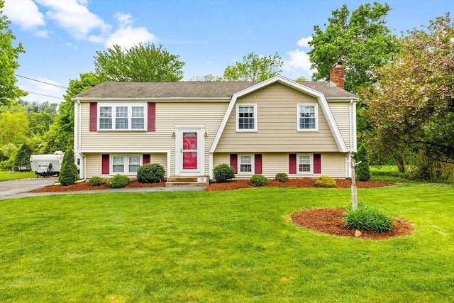 bi-level home with a chimney, a front yard, and a gambrel roof