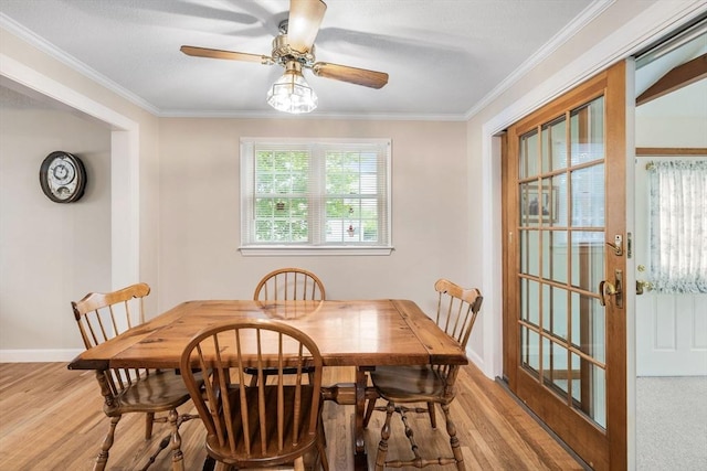 dining space with crown molding, light wood-style floors, a ceiling fan, and baseboards
