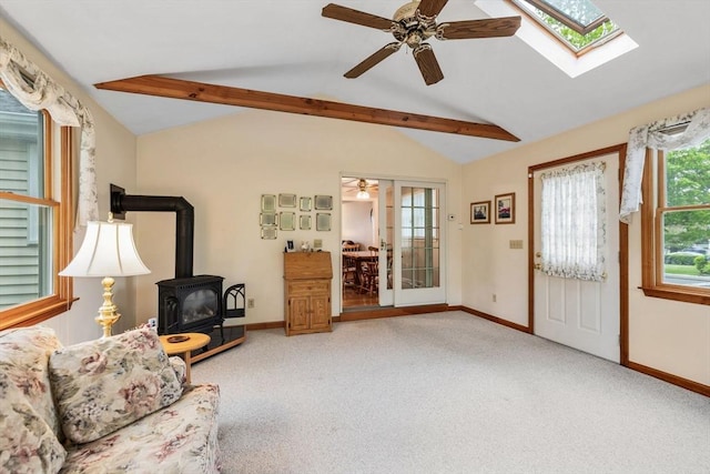 carpeted living area with a wood stove, a ceiling fan, and baseboards