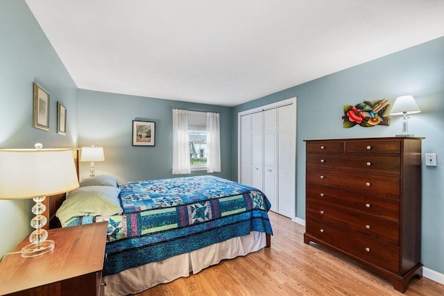 bedroom with light wood-type flooring, a closet, and baseboards