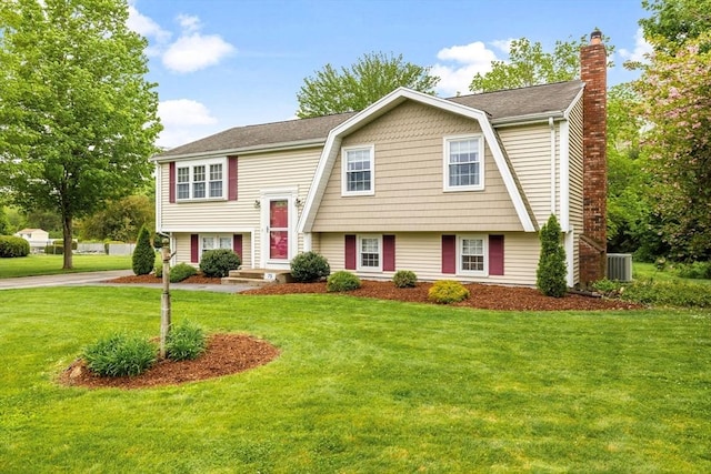 bi-level home with a chimney, a front lawn, central AC, and roof with shingles