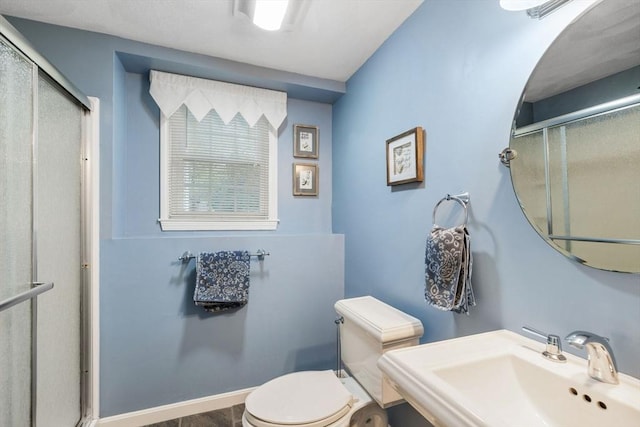 bathroom with a sink, a shower stall, and toilet