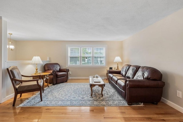 living area featuring wood finished floors, a textured ceiling, and baseboards