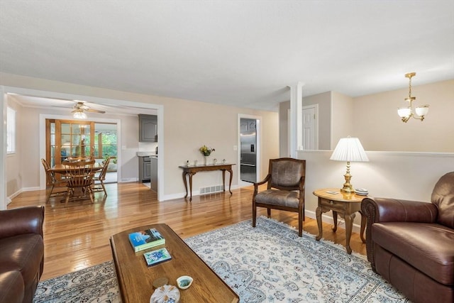 living room with light wood-type flooring, baseboards, and a ceiling fan