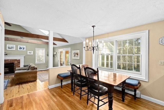 dining room with baseboard heating, a fireplace, light hardwood / wood-style floors, and a notable chandelier