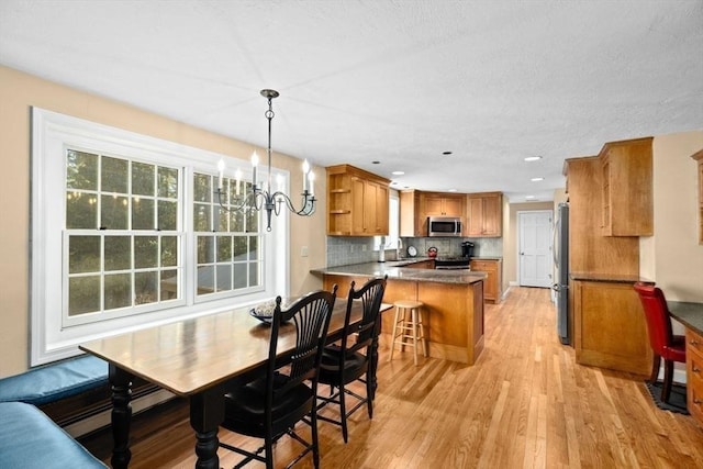 kitchen with pendant lighting, sink, a breakfast bar area, stainless steel appliances, and kitchen peninsula