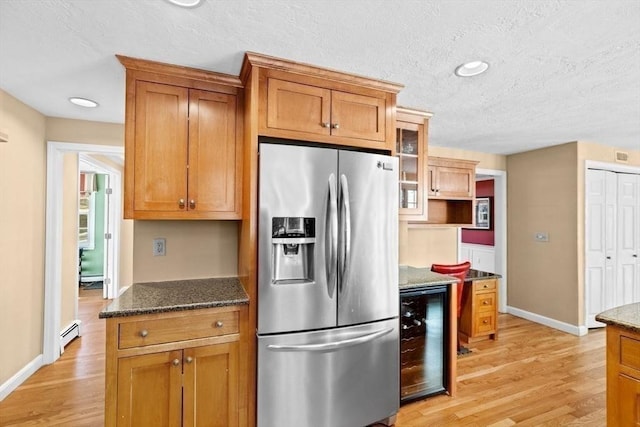 kitchen with a baseboard radiator, beverage cooler, stainless steel fridge, and dark stone counters