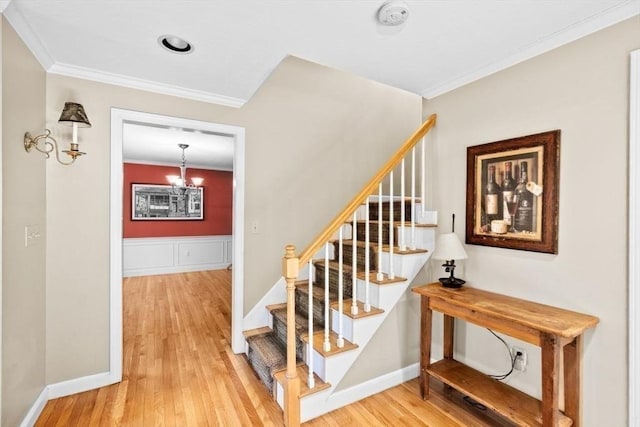 staircase with an inviting chandelier, hardwood / wood-style floors, and crown molding