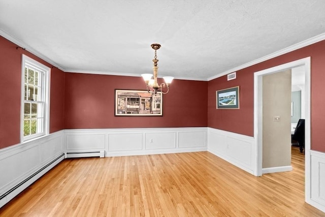 empty room featuring baseboard heating, crown molding, a chandelier, and light wood-type flooring