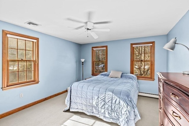 carpeted bedroom with multiple windows, a baseboard heating unit, and ceiling fan