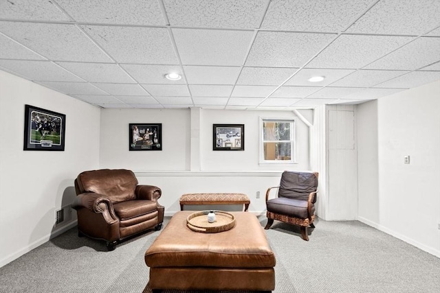 living area featuring a paneled ceiling and carpet flooring