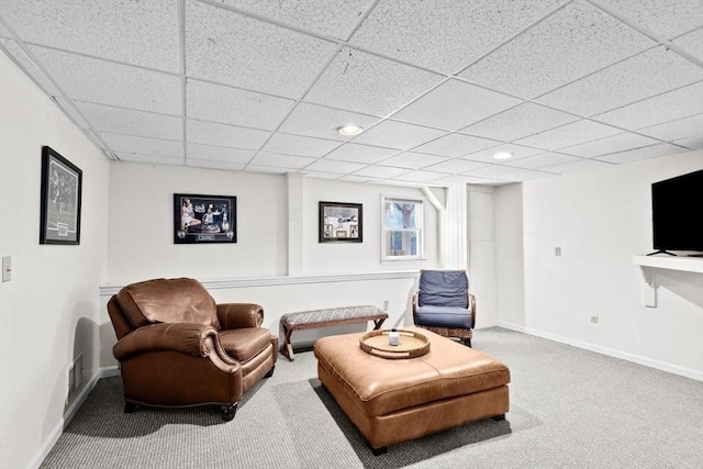 living area with a paneled ceiling and carpet flooring